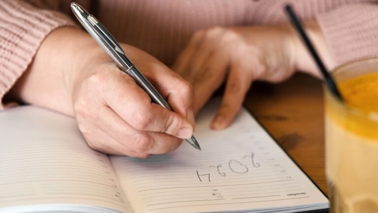 Close-up of hands writing in diary under